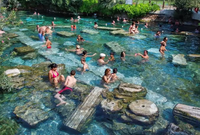 Bathers moving among submerged Roman drums in the warm clear water of the Antik Havuz