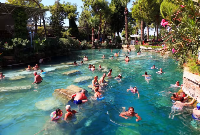 Open-air bathing at Pamukkale's Antik Havuz, palms and planting round sunken marble