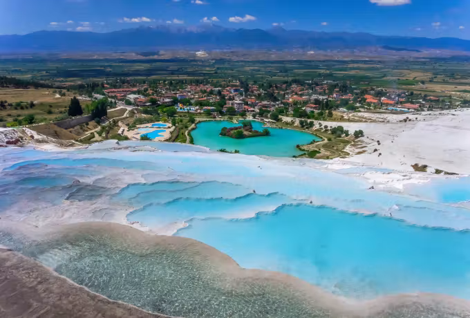 From the air, blue shelf pools above the green warm lake and the village at Pamukkale