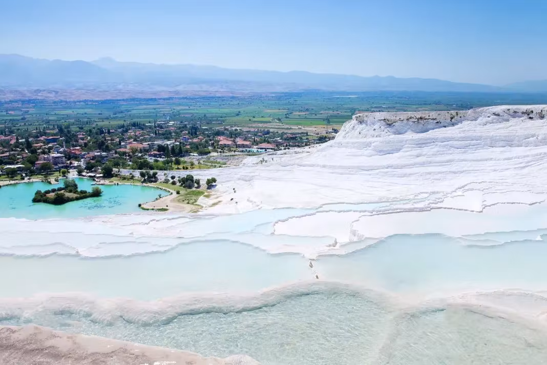 The whole chalk flank at Pamukkale falling toward the warm lake and the Denizli flats