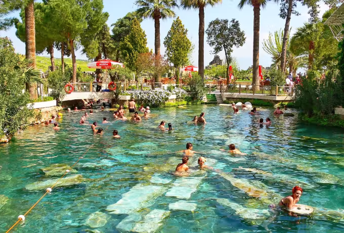 Long palm-lined basin with cut marble showing under the clear warm water at Pamukkale