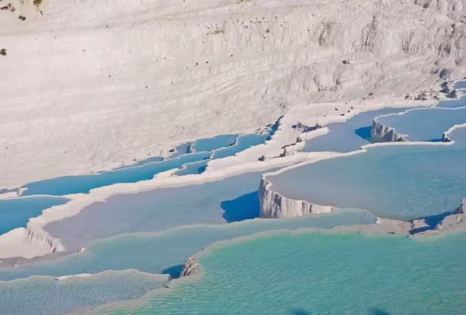Steep chalk front dropping to wide blue basins on the shelved hillside at Pamukkale
