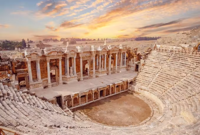Warm light picking out shafts and bays on the Hierapolis scene front above the benches