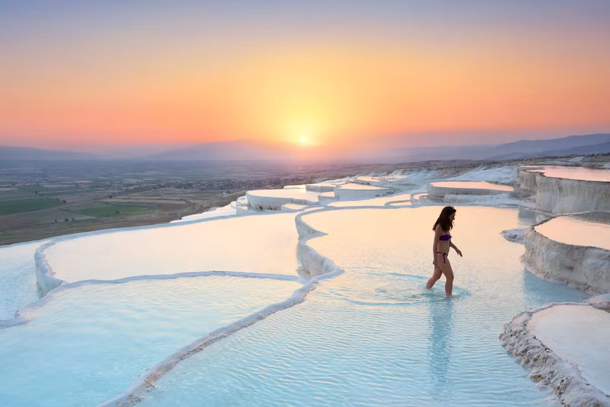 Ankle-deep on the shelves and heading toward the low sun over the wide plain, Pamukkale