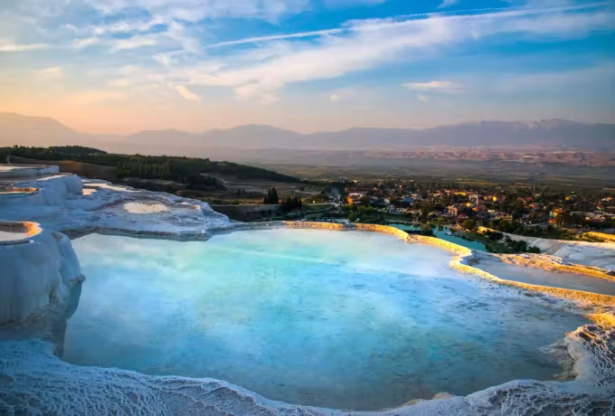 One broad sheet of pale colour in the mineral with lamps and far summits catching dusk, Pamukkale