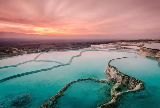 Green-blue water in the shelved basins under a soft rose and orange evening