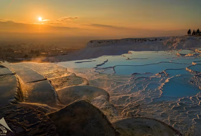 Raking sun turning the chalk ledges gold while the water takes the fading sky, Pamukkale
