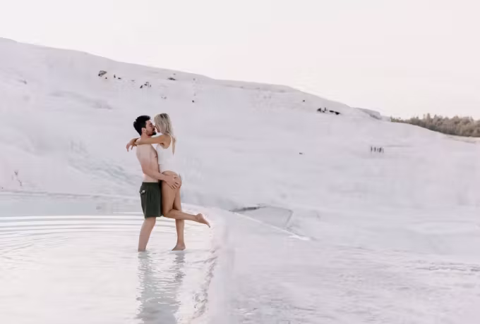 Embrace ankle-deep in warm water below the vast smooth chalk flank at Pamukkale