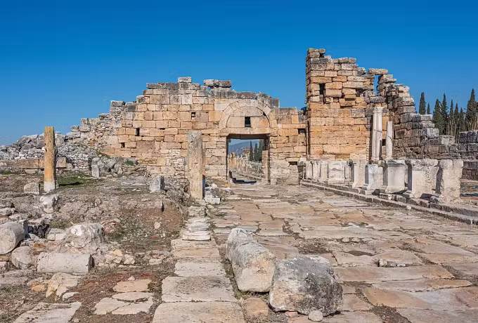 Broken stone entry at the far end of the Hierapolis avenue with drums along the slabs