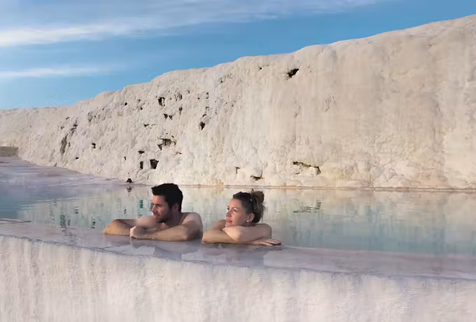 Two sitting in warm shallows directly under the great chalk face at Pamukkale