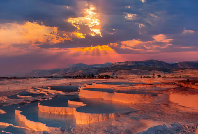 Whole flank taking a coppery cast as sunlight escapes under the overcast on the peaks, Pamukkale