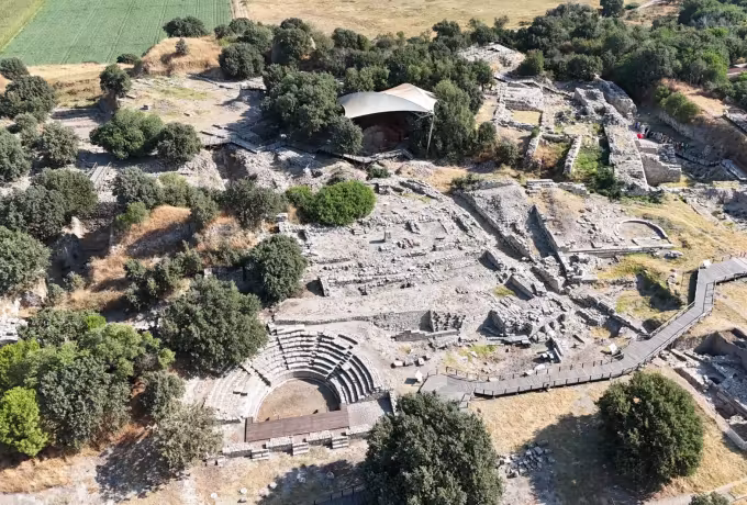 Whole Troy site from a drone: small odeon, tangled footings, a roof over the main trench