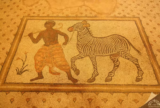 Golden gallery light bringing up every tessera in the beast's bands and the man's leggings, Sanliurfa