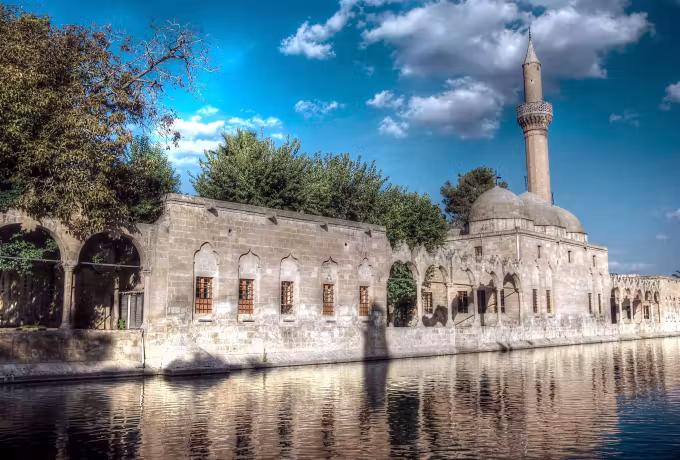 Mirror image of the arcaded mosque on flat water below deep blue banked with cloud