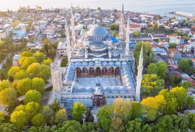 Drone shot taking in cupolas, six towers and the full arcaded forecourt ringed by trees, Istanbul