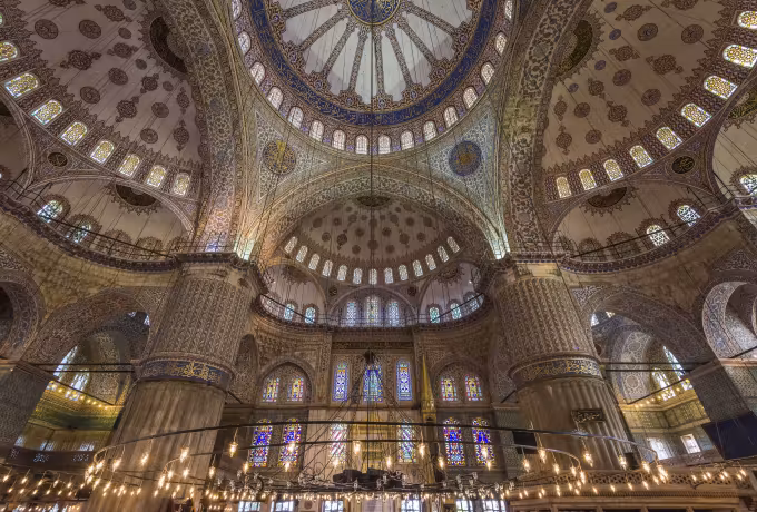 Central vault and tiled tribunes curving away above a circle of suspended fittings, Istanbul