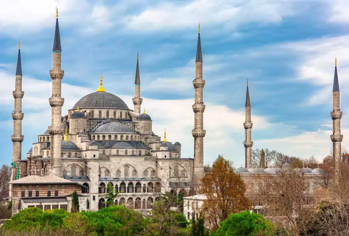 Flank view showing the stacked cupolas and four visible towers under drifting cloud, Istanbul