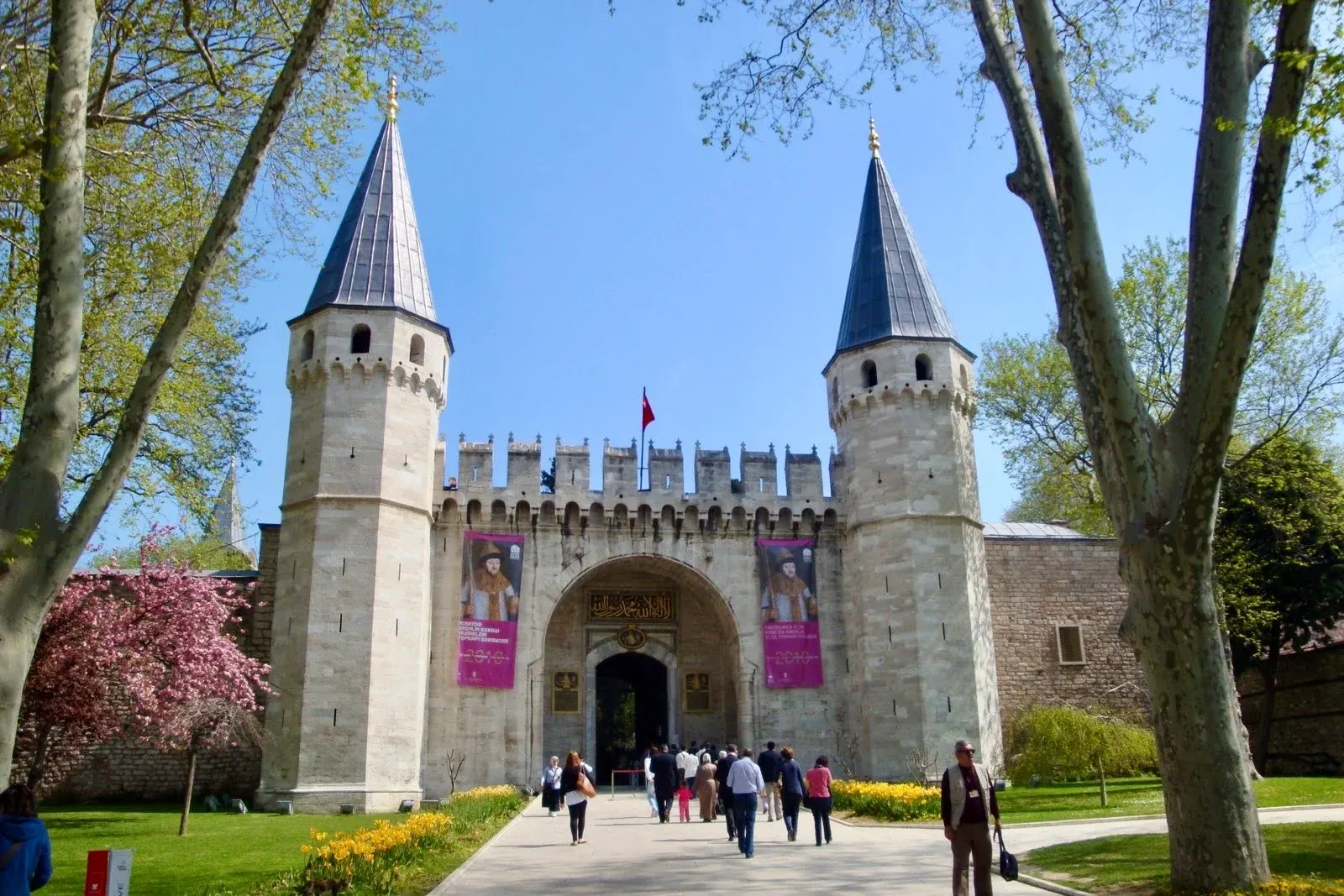Topkapı Palace's twin-towered Gate of Greeting, with visitors entering between spring flowerbeds