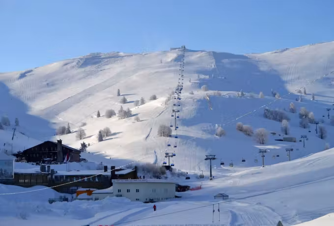 Lodges and pistes buried in snow at Uludag, a lift running up the open hill toward the top