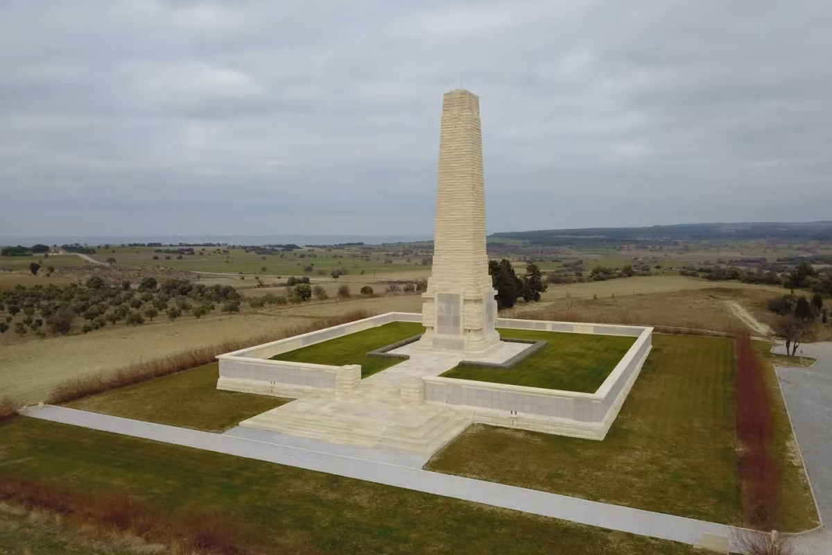 Drone view of the lone Cape Helles pillar standing on open turf at the peninsula tip