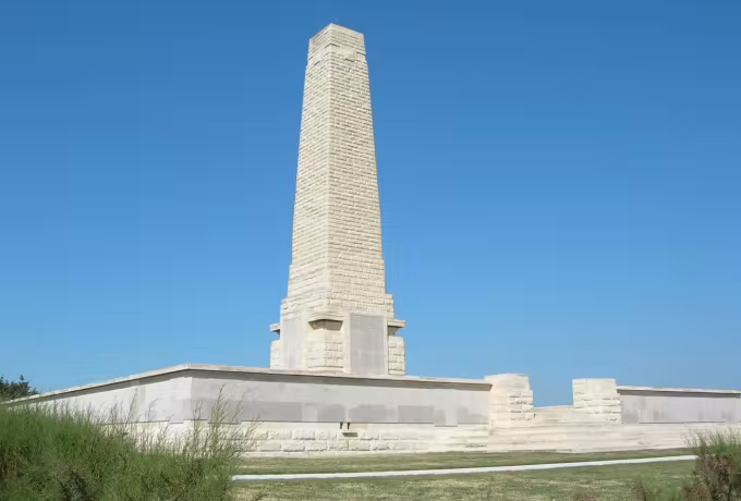 Fluted shaft of the Cape Helles monument with its low enclosing wall under clear sky