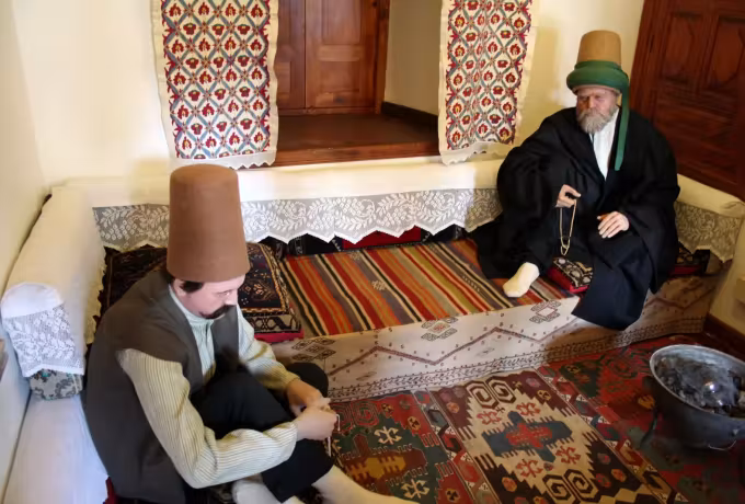 Set piece at the Konya Mevlana with carpets, low bolsters and two capped figures seated