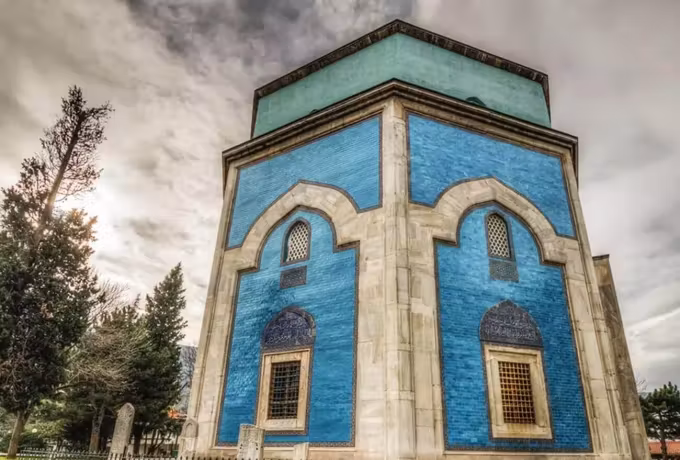 Blue-green tilework and pale stone framing on the Yesil Turbe in Bursa under grey cloud