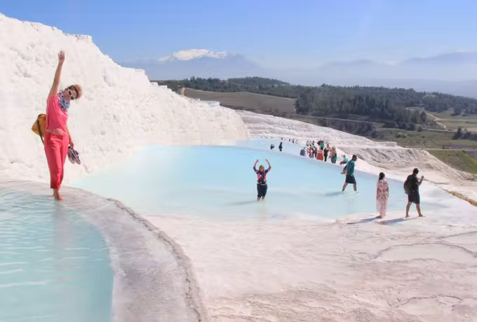 Bathers ankle-deep in the rimmed hollows under a big open summer ceiling, Pamukkale