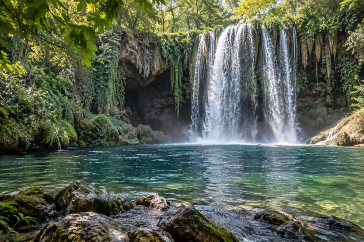 Upper Duden Waterfall in Antalya cascading into a green pool surrounded by leafy trees