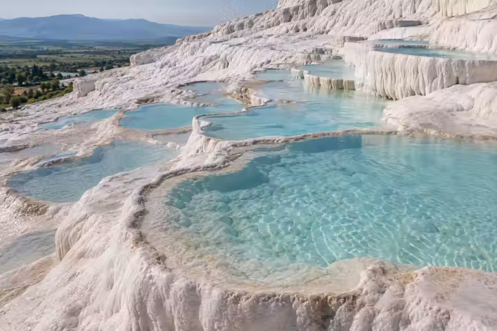 Clear shallow turquoise pools along scalloped white travertine terraces at Pamukkale
