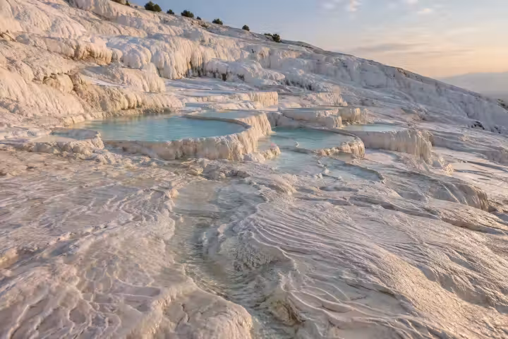 Shallow turquoise pools and rippled white travertine terraces at Pamukkale in morning light