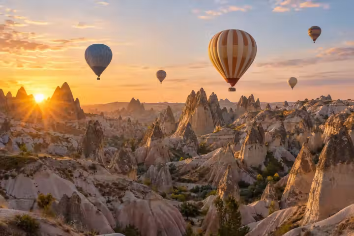 Hot air balloons over layered Cappadocia fairy chimneys at golden sunrise