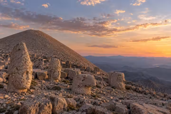 Ancient stone heads on Mount Nemrut with mountain views at sunset