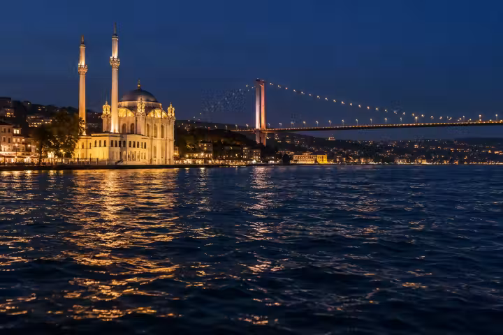 Illuminated Ortakoy waterfront and bridge reflected on the Bosphorus at night