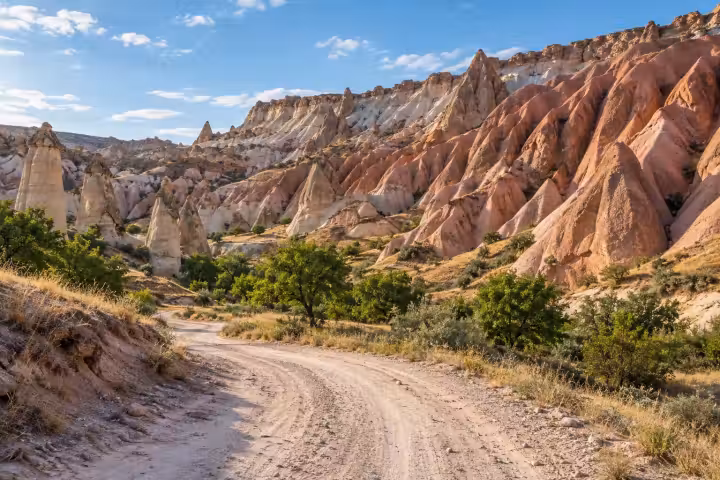 A winding valley track beneath pink and cream rock formations in Cappadocia