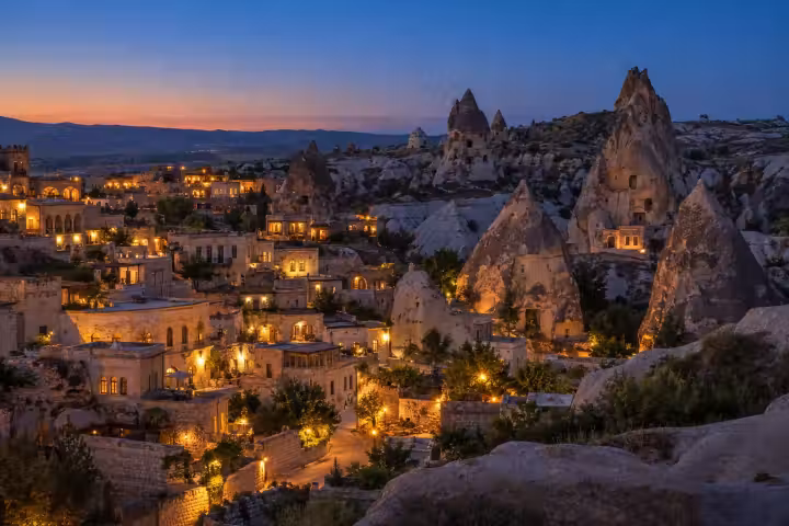 Warm evening lights among Cappadocia stone houses and fairy chimneys at twilight