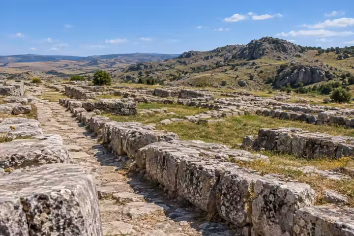 Weathered stone foundations and a paved path among the hills at Hattusa